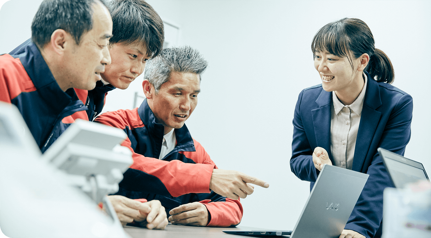 成田さんがノートパソコンを持って現場の人と話すシーン